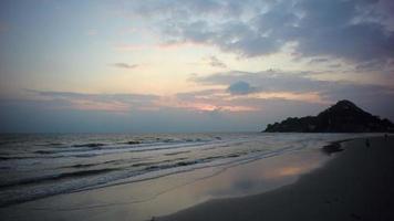 Wellen am Strand mit Sonnenuntergang und Bergen im Hintergrund, mit Audio