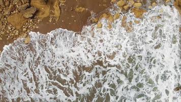 Vue aérienne de dessus des vagues de l'océan se brisent sur une plage de sable rocheux. majestueuses falaises, lagos, portugal video