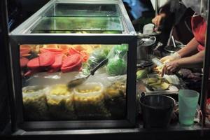 Various fruits in a glass cooler at a street food stall at a night market. photo