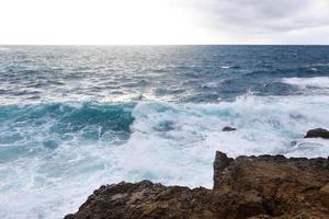 Waves hitting the rocky cliffs on the beach located in Cyprus photo