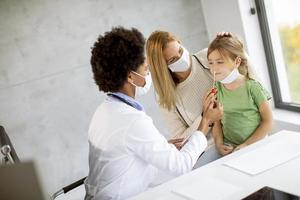 Pediatrician giving girl a COVID-19 test photo