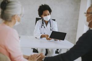 Masked mature couple receiving news from doctor photo