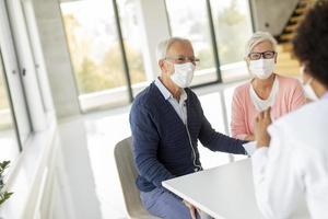 Mature couple in masks receiving news from doctor photo