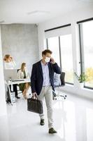 Vertical view of a masked businessman taking on phone and holding briefcase photo