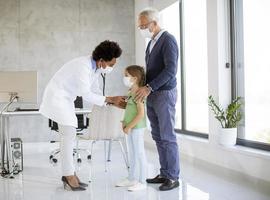 doctor examinando a una niña con abuelos presentes