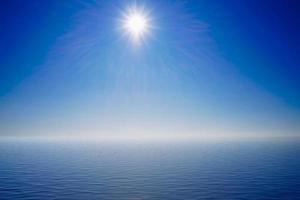 Seascape with a bright sun on a blue sky photo