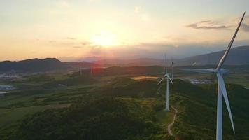 3 windturbines op de heuvelkant bij zonsondergang video
