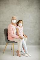 Vertical view of a grandmother in a chair with granddaughter wearing masks photo