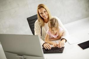 madre trabajando con hija en el regazo foto