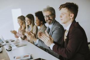 Business people applauding with man looking at camera photo