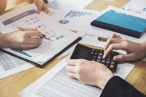 Business team analyzing income charts and graphs to plan marketing concept with using pen and calculator  for analysis photo