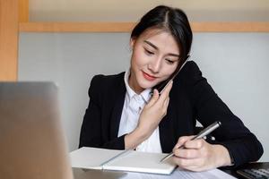 Businesswoman  calling and working at the office to verify the accuracy of the account using a calculator and laptop computer photo