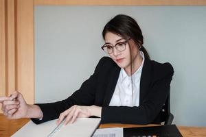 La empresaria con gafas está trabajando en la oficina para verificar la exactitud de la cuenta usando una calculadora. foto