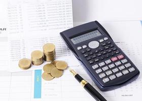 Calculadora y pila de monedas de dinero con pluma estilográfica para concepto de finanzas