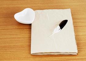 Old paper, feather, and heart-shaped cup on wooden desk for vintage concept photo