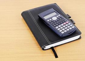 Business book and calculator on wooden desk background for business concept photo