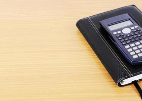 Calculator and business book on wooden desk background photo
