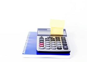 Casa de papel con calculadora y libro azul para el concepto de negocio sobre fondo blanco. foto