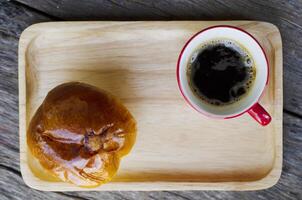 Espresso coffee red cup and bun on wood plate background photo