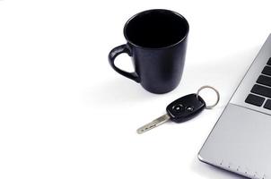 Black coffee cup and car key and laptop computer on white background for minimalist style concept with copy space for text photo