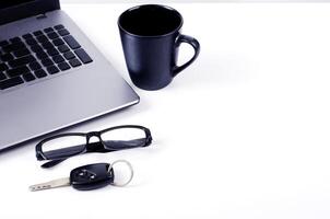 Black coffee, laptop, eyeglasses, and car keys on a white background photo