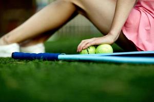 niña sentada en el césped de un campo de tenis con una raqueta de tenis foto