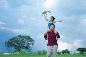 Child and father playing with kite in the park photo