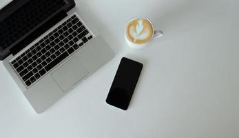 Computer laptop, coffee, and smartphone on background, top view. Copy space photo