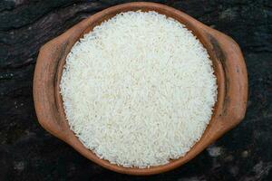 Jasmine rice in a clay pot on a wooden background photo