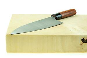 Kitchen knife and wooden butcher block countertop on a white background photo