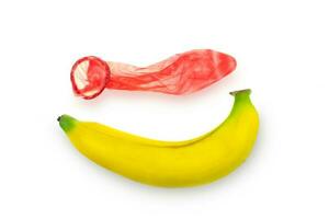 Condón rojo usado en un plátano sobre un fondo blanco.