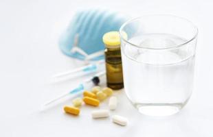 vaso de agua azul mascarilla médica y pastillas medicinales foto