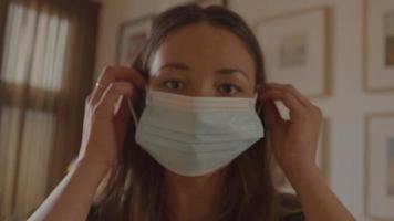 kvinna sätta på ansiktsmask tittar in i linsen video