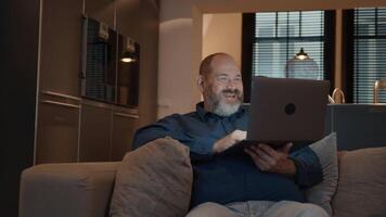 man met online bellen op laptop op de bank glimlachen video