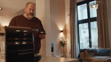 Mann mit dem Smartphone, der zur Kaffeemaschine geht, die Kaffee macht video