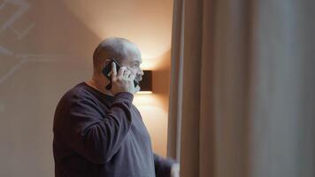 Man looking through window whilst talking on smartphone video