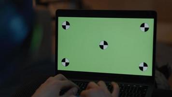 kvinna med hörlurar att skriva på bärbar dator med grön skärm