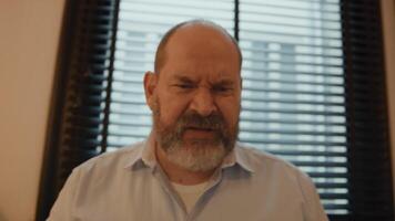 Man at table getting angry whilst having online call video