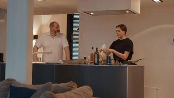 donna che prepara il pasto mentre parla con l'uomo in cucina video