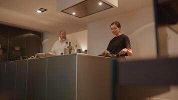 Mujer preparando comida mientras habla con el hombre en la cocina video