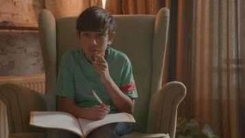 Boy in armchair talking and writing in exercise book video