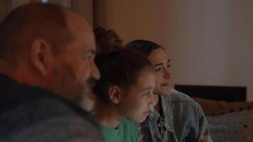 Family sitting on couch watching television smiling video