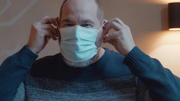 Man smiling putting on face mask looking into camera lens video