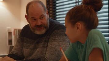 Man talking with girl doing her homework at table video