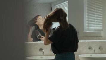 Woman using hairdryer in bathroom looking in mirror video