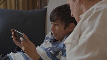 Frau beobachtet Jungen mit Spielekonsole auf der Couch video