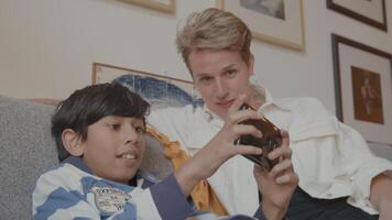 Boy playing with game console and woman watching on couch video