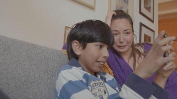 Boy playing with game console and woman watching on couch video