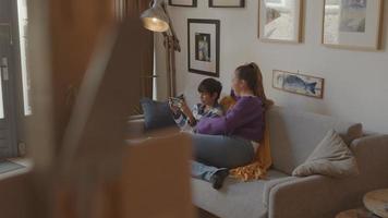 Frau beobachtet Jungen mit Spielekonsole auf der Couch video