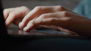 Manos de mujer escribiendo en el portátil mientras ve la pantalla video